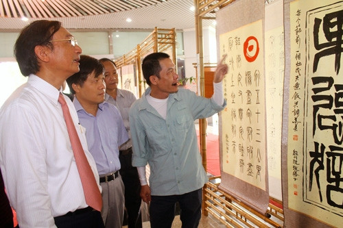 TS Nguyễn Xuân Thắng, Thành viên HĐTV Tập đoàn Dầu khí Việt Nam và TS Phan Ngọc Trung, Viện trưởng Viện Dầu khí đang nghe thư pháp gia Lê Quốc Việt giới thiệu về một bài thơ của Bác