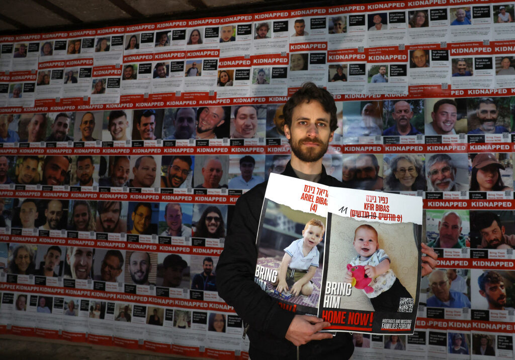 Anh Eylon Keshet cầm áp phích về các thành viên gia đình bị giam giữ khi anh xem “Tiếng nói từ đường hầm” - một cuộc triển lãm do Dự án Chuỗi người 7/10 tổ chức nhằm nêu bật hoàn cảnh khốn khổ của các con tin Israel ở Dải Gaza. Triển lãm diễn ra tại London, Anh ngày 15/1/2024. Ảnh: Reuters.