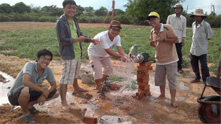 Nhóm sinh viên triển khai dự án trên cánh đồng mẫu. Nước bắt đầu phun liên tử máy bơm sử dụng năng lượng mặt trời. 