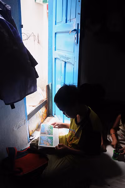 Nhà nhỏ thiếu sáng nên bé Thế Trung con trai chị tận dụng không gian trước cửa để đọc sách cũng là cách tiết kiệm điện