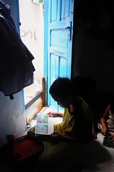 Nhà nhỏ thiếu sáng nên bé Thế Trung con trai chị tận dụng không gian trước cửa để đọc sách cũng là cách tiết kiệm điện