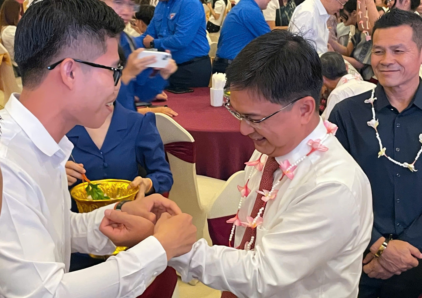 Sinh viên Lào, Campuchia và ông Nguyễn Mạnh Cường thực hiện nghi thức buộc chỉ cổ tay.