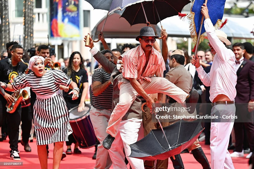 Nhóm nghệ sĩ gây chú ý với tiết mục biểu diễn náo loạn thảm đỏ ra mắt phim O Agente Secreto (L'Agent Secret/The Secret Agent) của đạo diễn Kleber Mendonça Filho. Phim lấy bối cảnh Brazil vào năm 1977, kể về chuyên gia công nghệ ngoài 40 tuổi Marcelo chạy trốn đến thành phố Recife vào đúng dịp diễn ra lễ hội hóa trang carnival. Ông hy vọng đoàn tụ với con trai, nhưng lại phát hiện ra thành phố này ẩn chứa nhiều nguy hiểm hơn anh tưởng. Ảnh: Getty Images.