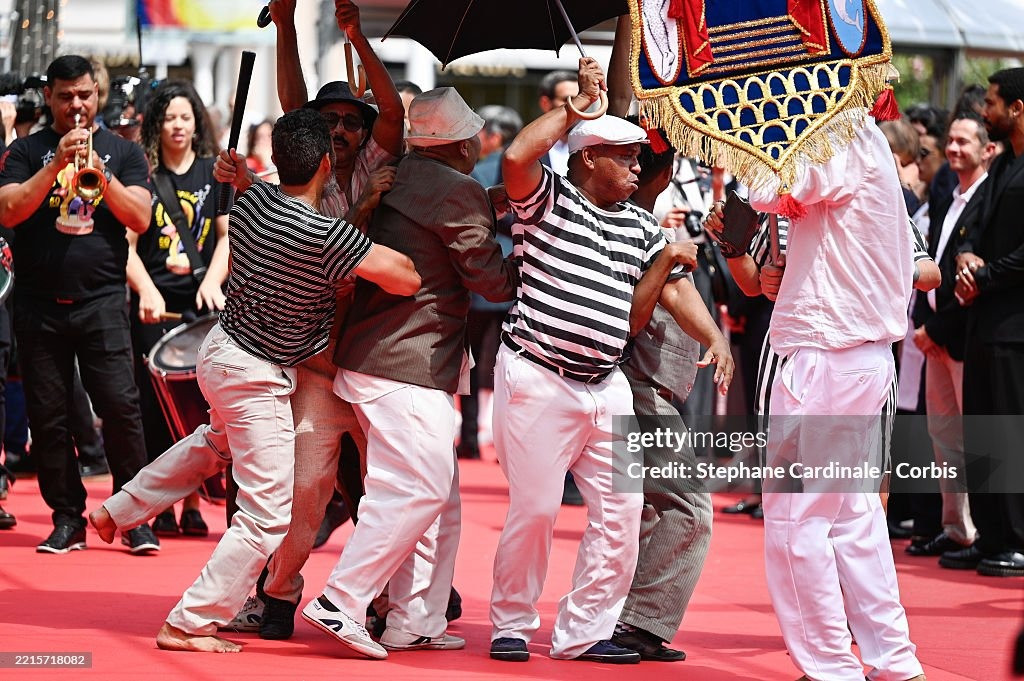 Nhóm nghệ sĩ gây chú ý với tiết mục biểu diễn náo loạn thảm đỏ ra mắt phim O Agente Secreto (L'Agent Secret/The Secret Agent) của đạo diễn Kleber Mendonça Filho. Phim lấy bối cảnh Brazil vào năm 1977, kể về chuyên gia công nghệ ngoài 40 tuổi Marcelo chạy trốn đến thành phố Recife vào đúng dịp diễn ra lễ hội hóa trang carnival. Ông hy vọng đoàn tụ với con trai, nhưng lại phát hiện ra thành phố này ẩn chứa nhiều nguy hiểm hơn anh tưởng. Ảnh: Getty Images.