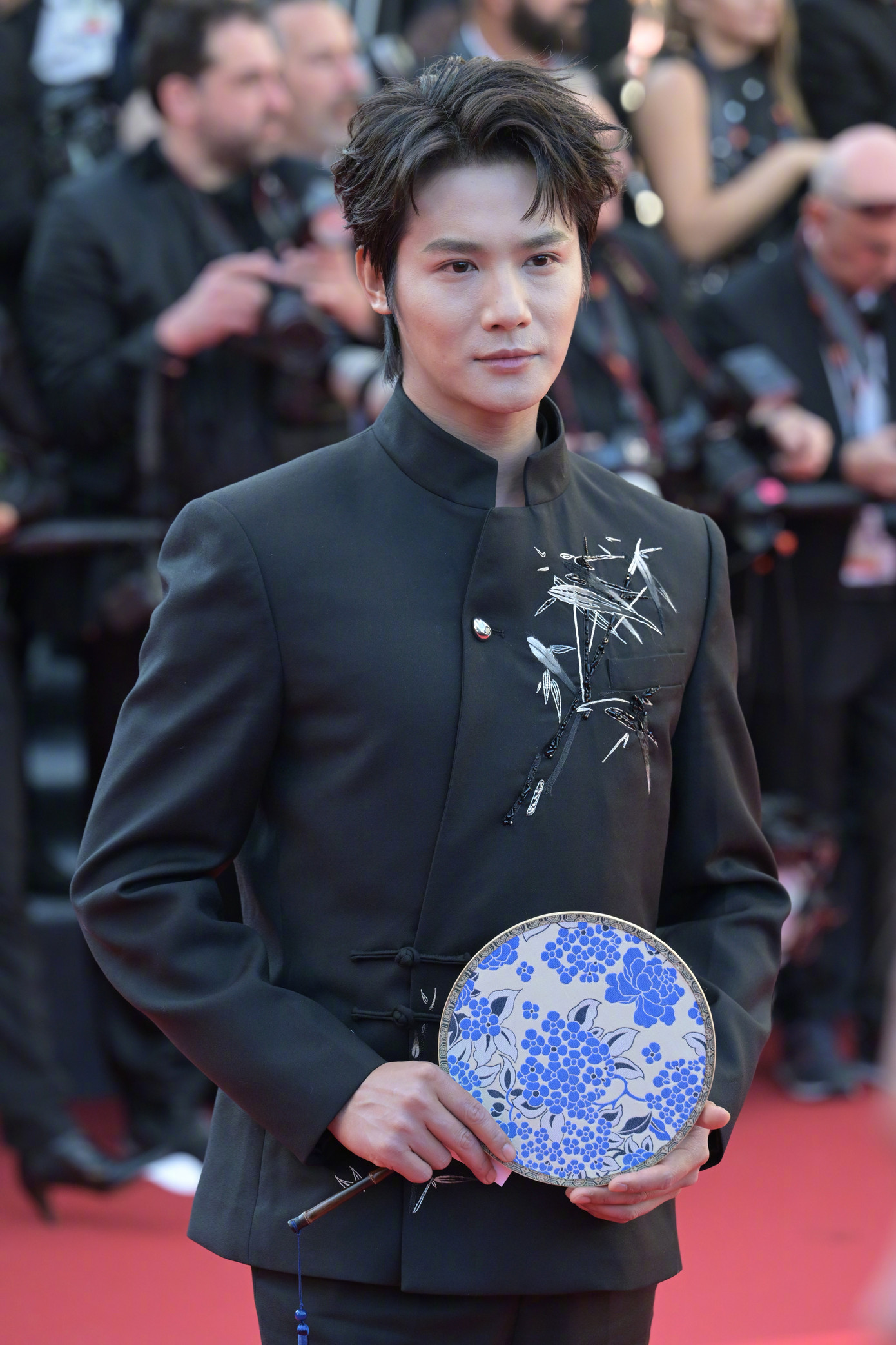 Nam diễn viên Trịnh Nghiệp Thành mặc trang phục đậm nét văn hóa Trung Quốc với họa tiết lá tre trên áo và quạt tròn. Tuy vậy, ngôi sao sinh năm 1993 mờ nhạt trên thảm đỏ Cannes. Ảnh: Weibo.