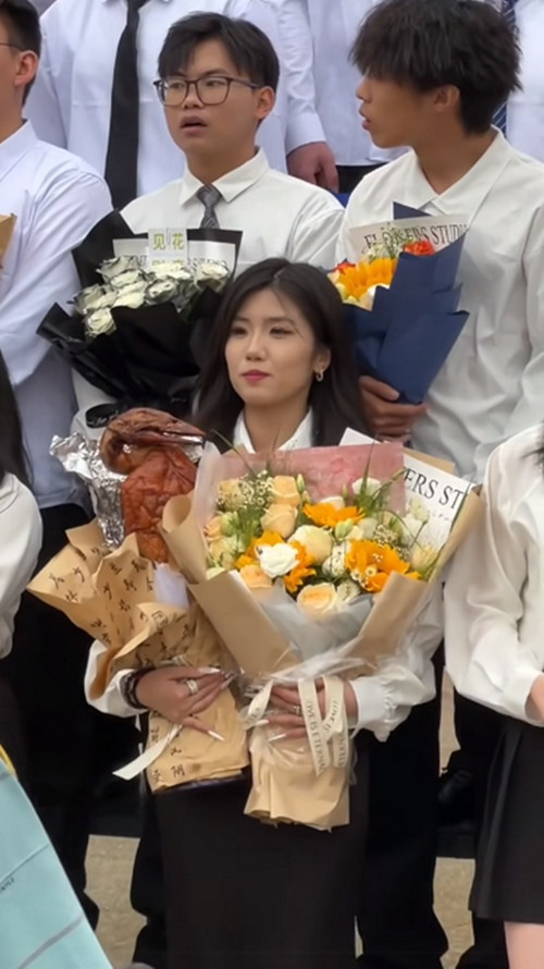 Nữ sinh viên ôm một bó hoa tươi và một "bó hoa vịt quay". Ảnh: T-Time HK.