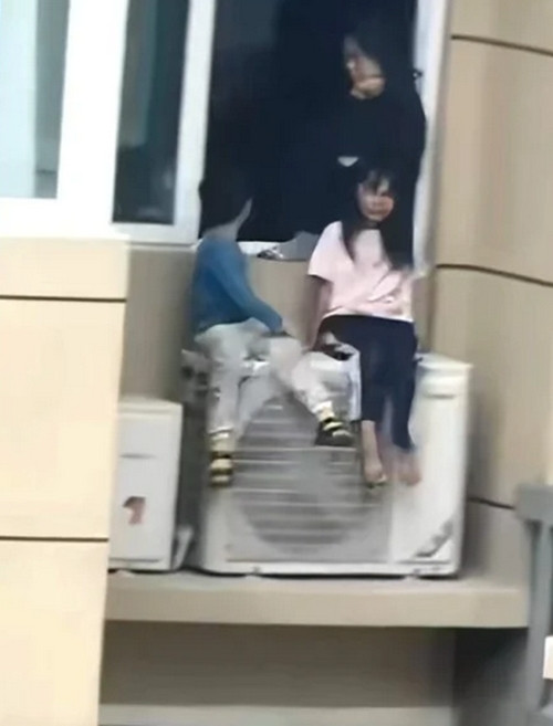 2 em nhỏ bị mẹ cho ngồi trên cục nóng điều hòa ở ngoài trời - trên tầng 23 - trong khi bố mẹ cãi nhau. Ảnh: China News. 2 em nhỏ bị mẹ cho ngồi trên cục nóng điều hòa ở ngoài trời - trên tầng 23 - trong khi bố mẹ cãi nhau. Ảnh: China News.