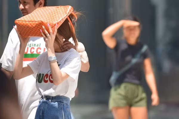 Người đi bộ che nắng trong một đợt nóng của năm nay ở Bangkok (Thái Lan). Ảnh: Rachen Sageamsak/ Xinhua.