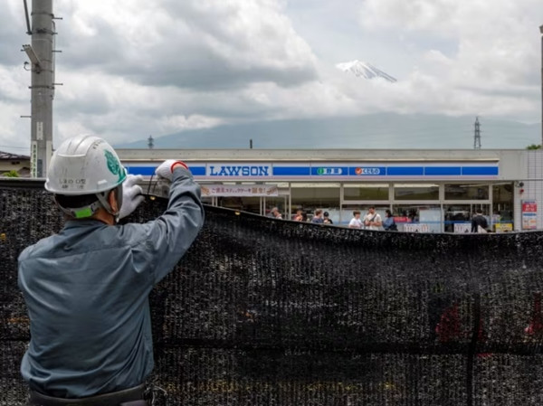 Một công nhân đang dựng tấm màn ngăn để che bớt khung cảnh núi Phú Sĩ (Nhật Bản) vào ngày 21/5/2024, nhằm làm giảm số du khách tập trung ở đây ngắm núi nhưng xả đầy rác. Ảnh: AFP. Một công nhân đang dựng tấm màn ngăn để che bớt khung cảnh núi Phú Sĩ (Nhật Bản) vào ngày 21/5/2024, nhằm làm giảm số du khách tập trung ở đây ngắm núi nhưng xả đầy rác. Ảnh: AFP.