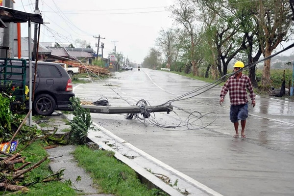 Một người dân ở Philippines đi qua cột điện bị đổ do siêu bão Yutu vào cuối tháng 10/2018. Ảnh: AP. Một người dân ở Philippines đi qua cột điện bị đổ do siêu bão Yutu vào cuối tháng 10/2018. Ảnh: AP.