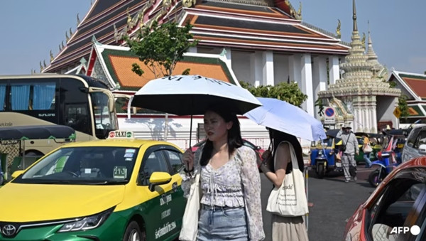 Du khách cố che nắng ở Bangkok vào tháng 4 năm nay. Ảnh: Lillian SUWANRUMPHA/ AFP.
