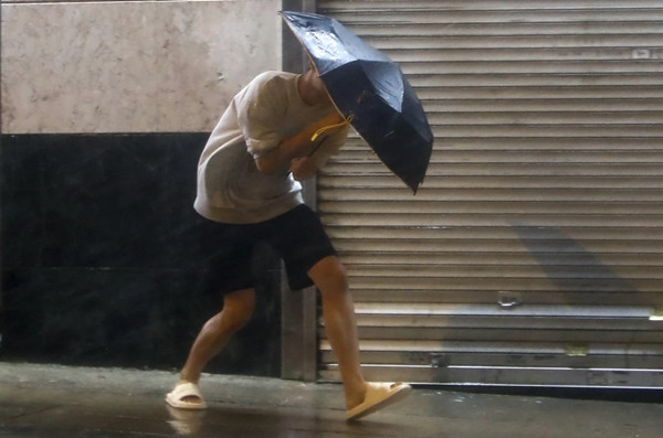 Một người cầm ô đi trong mưa gió do siêu bão Saola ở Hong Kong (Trung Quốc) vào tháng 9/2023. Ảnh: Daniel Ceng/ AP.