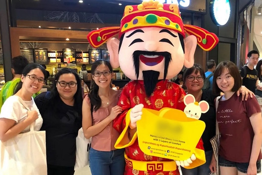 Người Singapore chụp ảnh với người đóng vai Thần Tài. Ảnh: Bigtop SG.