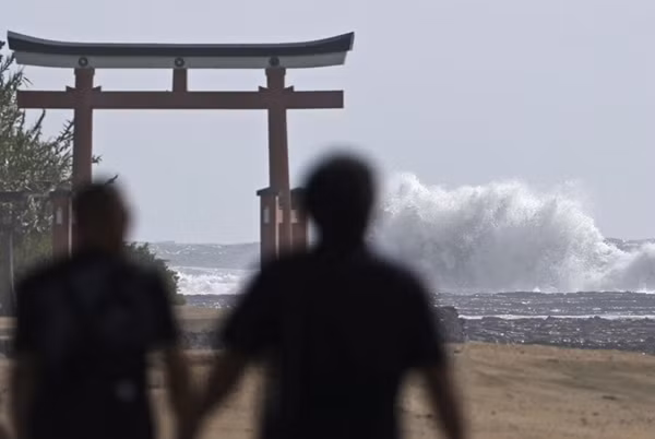 Người dân đi gần một vùng bờ biển ở Miyazaki, phía Tây Nhật Bản, và nhìn sóng lớn khi bão Shanshan đang đến gần. Ảnh: Hidetaka Komukai/ Kyodo News via AP.