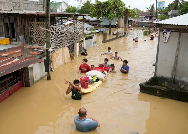 Người dân Philippines lội trong nước ngập do bão Noru năm 2022. Ảnh: Aaron Favila/ AP.