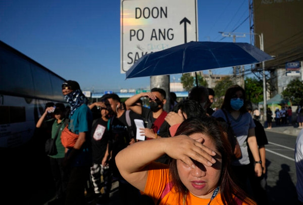 Người dân cố che nắng khi đợi ở một bến xe bus tại Quezon (Philippines). Ảnh: AARON FAVILA/ AP. Người dân cố che nắng khi đợi ở một bến xe bus tại Quezon (Philippines). Ảnh: AARON FAVILA/ AP.