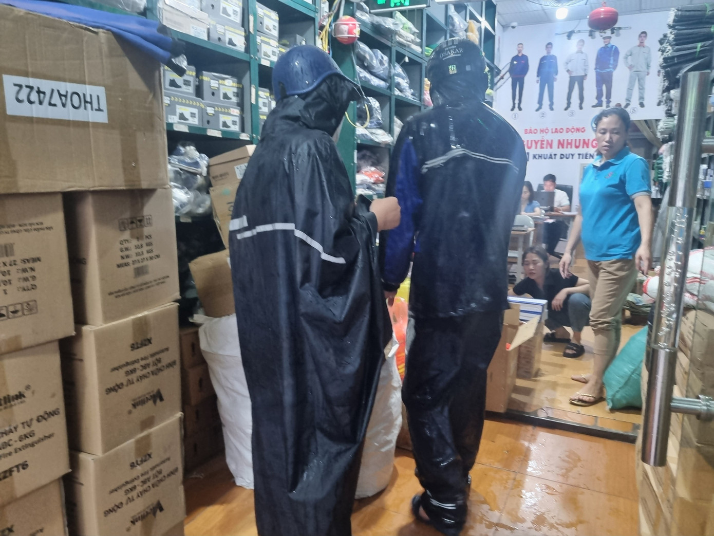 Khách mặc áo mưa tấp nập vào cửa hàng mua bình cứu hỏa, thang dây... (ảnh: Ngọc Mai).