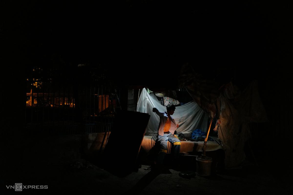 Chiếc lán che bằng những tấm bạt gỗ tạm bợ, được vợ chồng ông Đăng dựng bên hàng rào Cung Điền kinh, là nơi trở về sau mỗi ca làm việc. Ông Đăng tranh thủ thay quần áo lao động, ngả lưng ngủ đến 5h, rồi đi bộ ra đường lớn bắt hai chuyến xe buýt về nhà. Ông cho biết, hiện Công ty Minh Quân đã trả cho ông trước 3 tháng lương, còn nợ 4 tháng nữa họ hẹn ngày 10/7 sẽ gặp. Chiếc lán che bằng những tấm bạt gỗ tạm bợ, được vợ chồng ông Đăng dựng bên hàng rào Cung Điền kinh, là nơi trở về sau mỗi ca làm việc. Ông Đăng tranh thủ thay quần áo lao động, ngả lưng ngủ đến 5h, rồi đi bộ ra đường lớn bắt hai chuyến xe buýt về nhà. Ông cho biết, hiện Công ty Minh Quân đã trả cho ông trước 3 tháng lương, còn nợ 4 tháng nữa họ hẹn ngày 10/7 sẽ gặp.