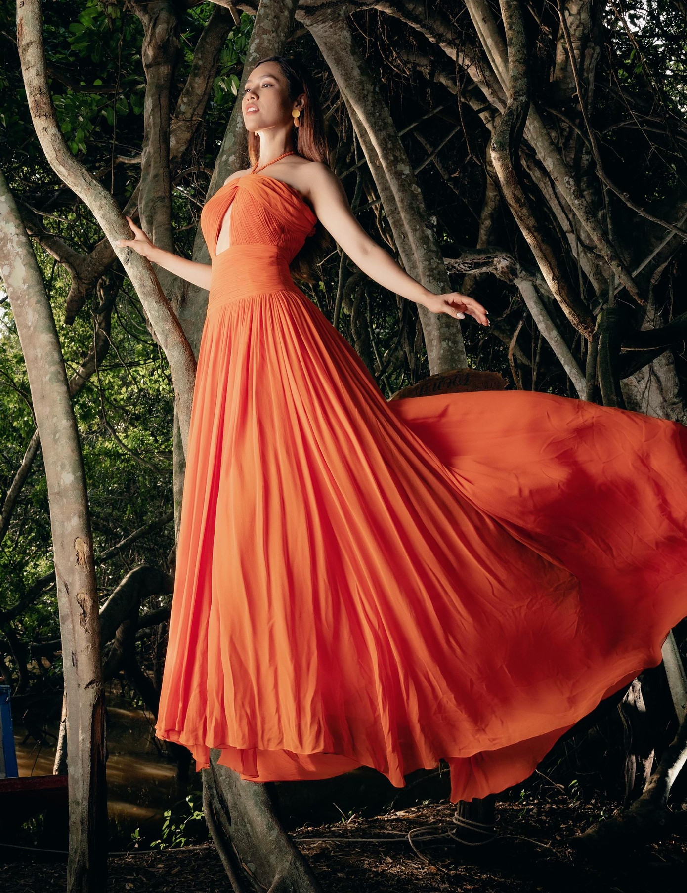 Bộ váy tông màu cam nổi bật với phần tùng váy xoè bay bổng mang lại cho Á hậu Việt Nam 2010 vẻ đẹp 'thoát tục' tựa như một nàng tiên nữ đang hoà mình vào thiên nhiên.