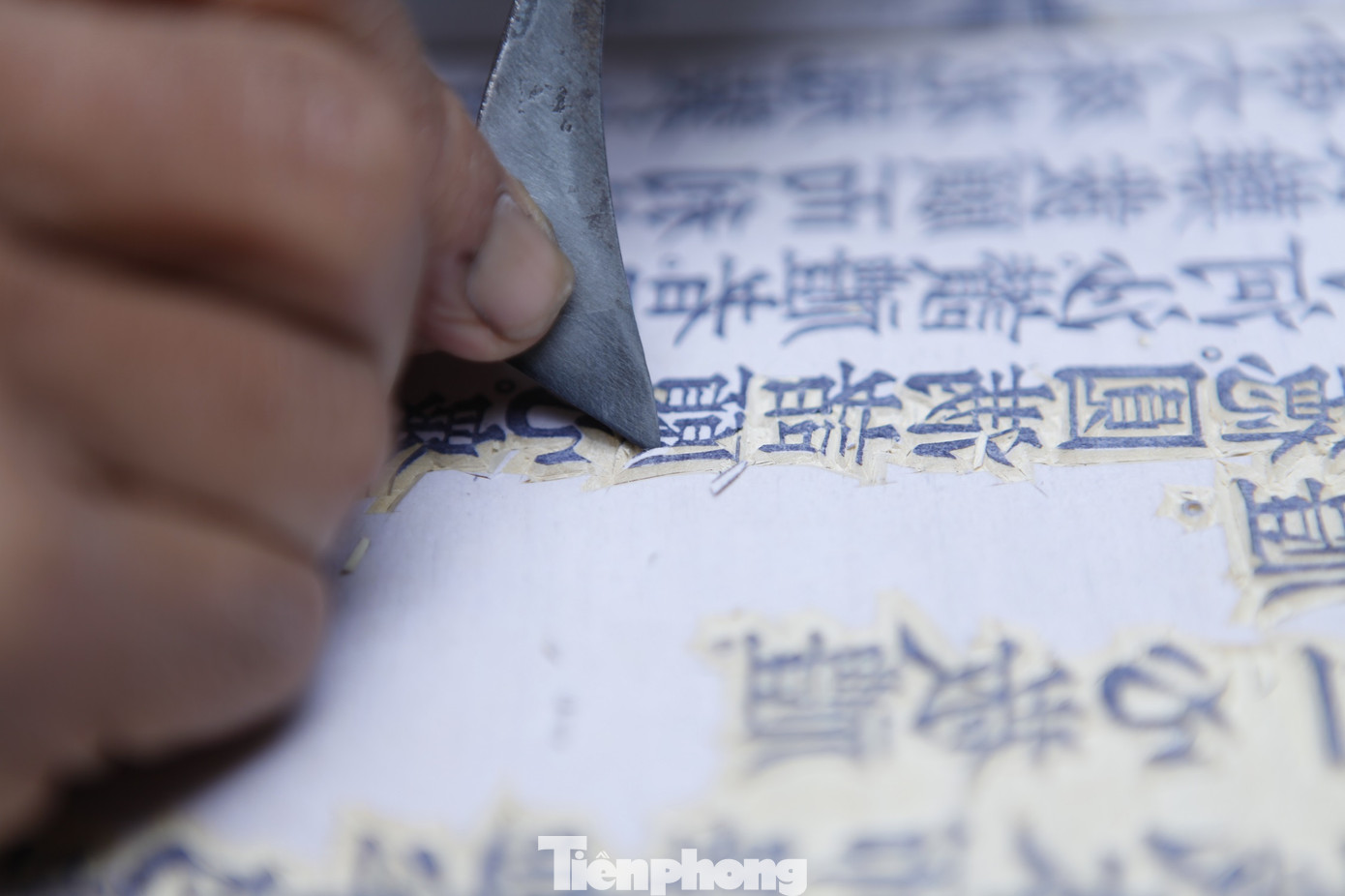 Anh Thạo mất hàng tiếng đồng hồ mới có thể khắc xong một chữ trên tấm ván gỗ. Nếu không cẩn trọng, chỉ một chút sơ sẩy, sai một nét chữ là hỏng cả bản khắc, anh mất công sức mấy ngày. Ảnh: Nguyễn Thắng
