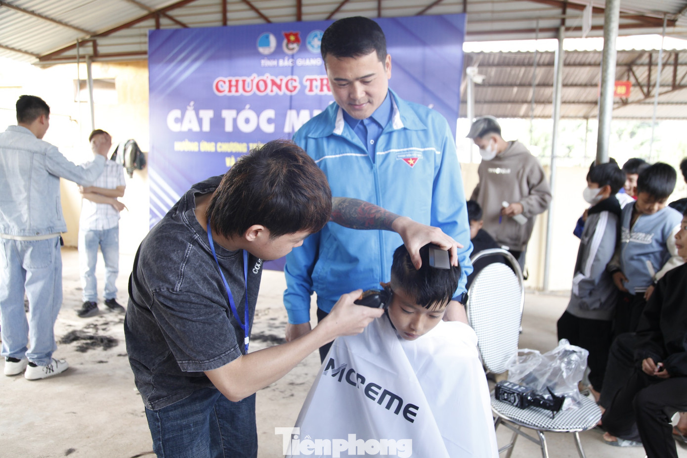 Thanh niên tình nguyện cắt tóc miễn phí cho trẻ em. Ảnh: Nguyễn Thắng