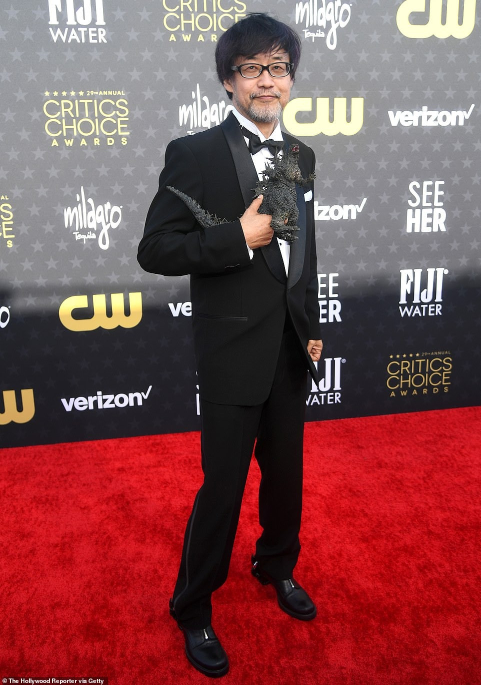 Nhà làm phim Nhật Bản Takashi Yamazaki trông lịch sự với vest đen. Tuy nhiên, không ai giải thích được lý do ông mang phụ kiện là mô hình Godzilla lên thảm đỏ. Ảnh: Getty Images. Nhà làm phim Nhật Bản Takashi Yamazaki trông lịch sự với vest đen. Tuy nhiên, không ai giải thích được lý do ông mang phụ kiện là mô hình Godzilla lên thảm đỏ. Ảnh: Getty Images.