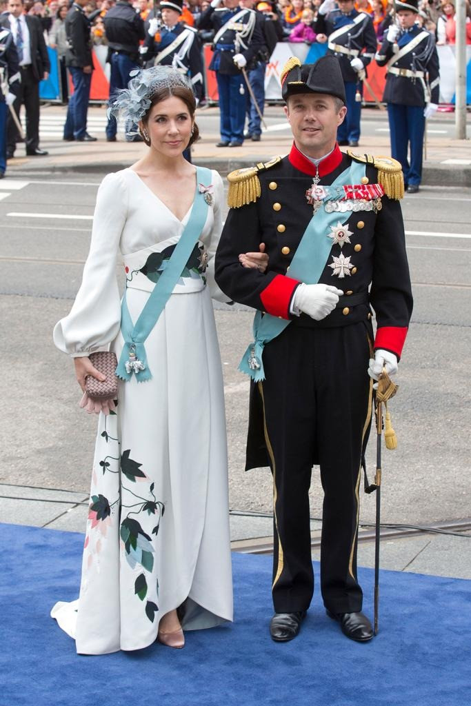 Khi tham dự lễ đăng cơ của Vua Hà Lan Willem-Alexander và Hoàng hậu Maxima vào năm 2013, Mary chọn váy trắng dài tay xẻ ngực màu trắng in hình hoa lá. Cùng với cách phối phụ kiện tinh tế, vừa đủ, Mary trông thanh tao, dịu dàng và mang đến cảm giác pha trộn vẻ đẹp Đông - Tây. Ảnh: Getty Images.