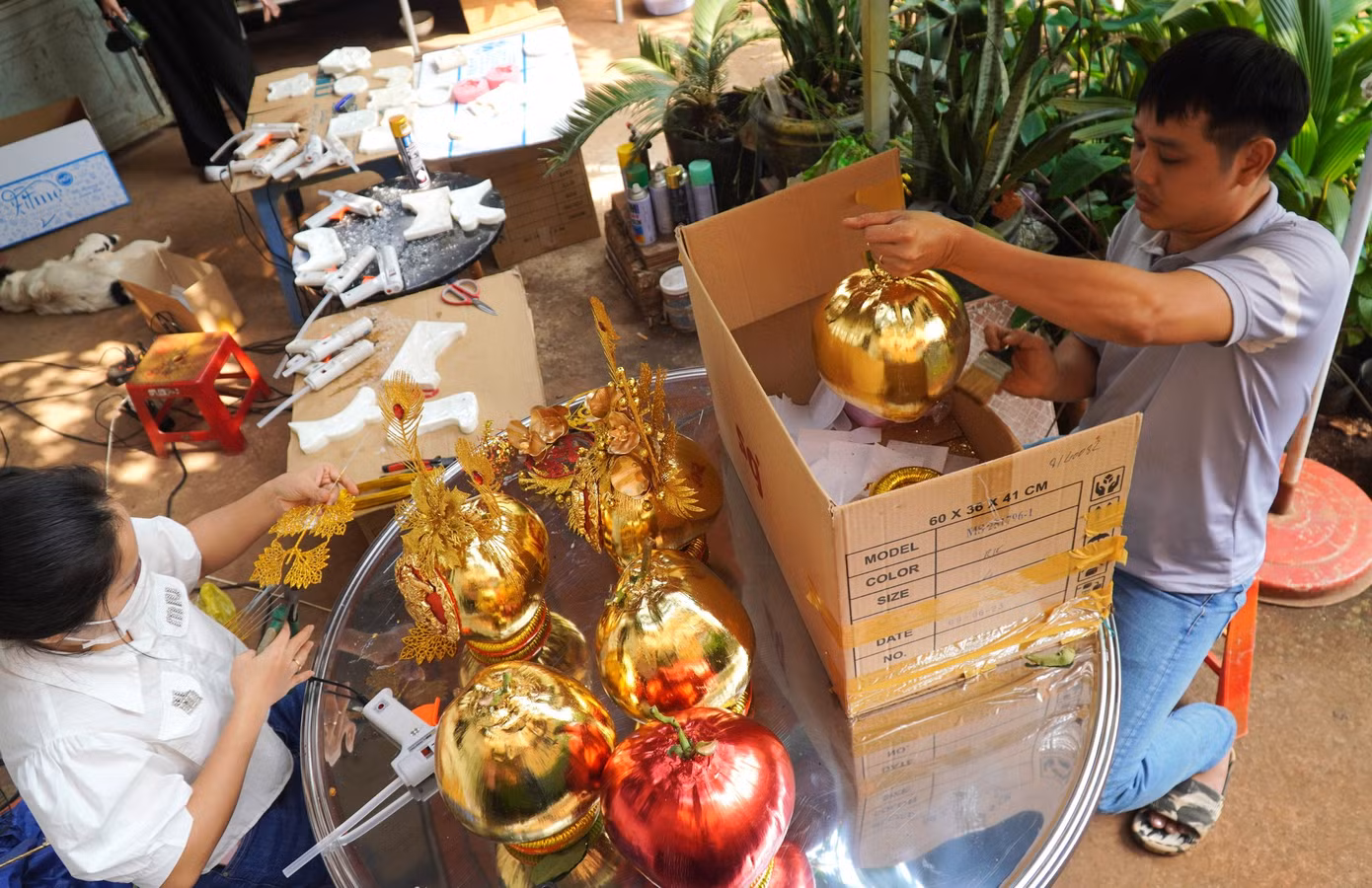 Vợ chồng anh Nguyễn Anh Vũ đang tất bật đổ khuôn vật liệu trang trí, dát vàng và gắn phụ kiện hoa lá cho những cặp dừa. Vợ chồng anh Nguyễn Anh Vũ đang tất bật đổ khuôn vật liệu trang trí, dát vàng và gắn phụ kiện hoa lá cho những cặp dừa.