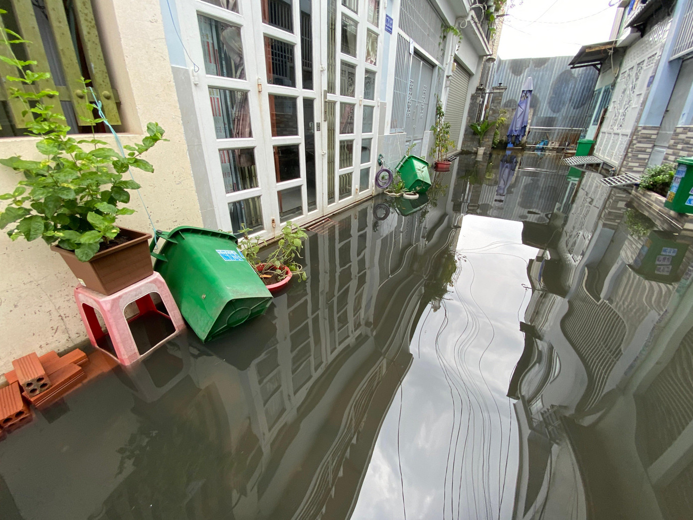 Nước ngập liên tục nên người dân phải dùng dây buộc thùng rác để tránh bị trôi mất. Ảnh ghi nhận tại hẻm 17 đường Tam Bình.
