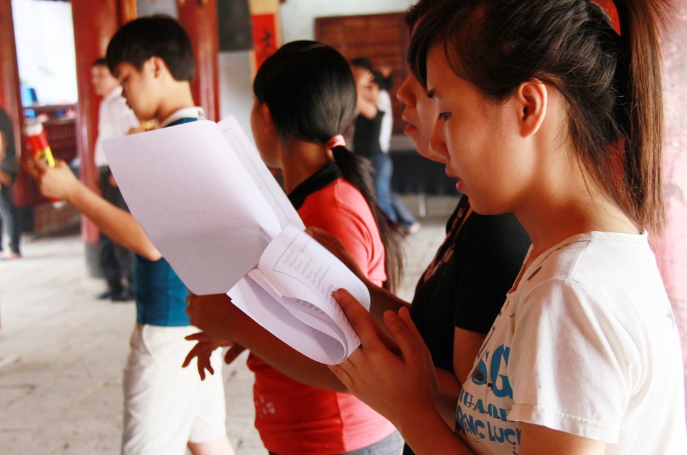 Hai mẹ con một thí sinh chép sẵn lời khấn vào giấy để đọc. Ảnh: Trường Phong