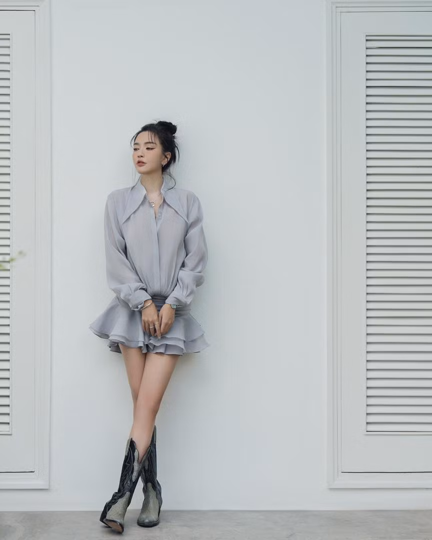 Nữ ca sĩ Bích Phương phối thiết kế đầm sơ mi cùng bốt cao cổ và tóc búi cao gọn gàng.