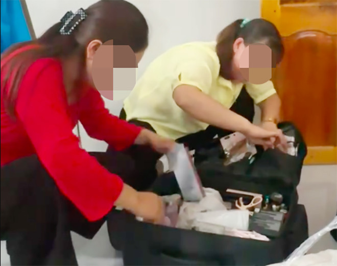 Người nhà chú rể kiểm tra các túi đồ mà hai cô gái làm nghề trang điểm mang theo. Ảnh: Chụp màn hình.