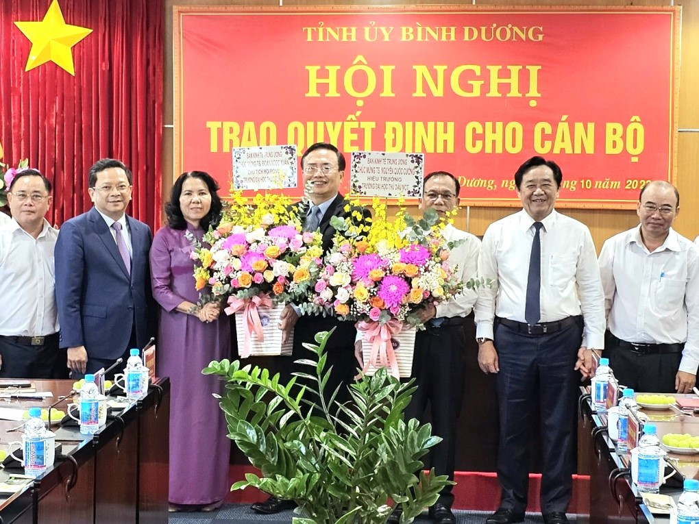 Tiến sĩ Đoàn Ngọc Xuân (thứ tư từ trái sang) và tiến sĩ Nguyễn Quốc Cường (thứ ba từ phải sang) nhận hoa chúc mừng từ lãnh đạo Ban Kinh tế Trung ương và Tỉnh ủy Bình Dương