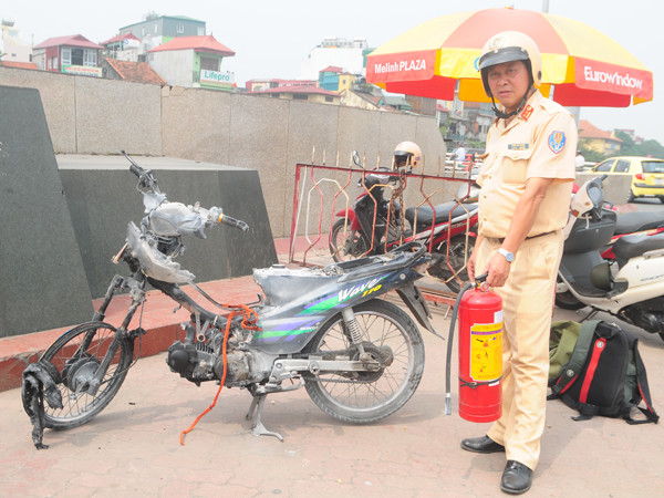 Trung tá Phạm Văn Cương, Đội Cảnh sát giao thông số 1 -CAHN bên chiếc xe bị cháy. Ảnh: Tuấn Nguyễn
