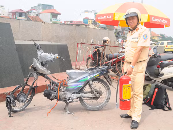 Trung tá Phạm Văn Cương, Đội Cảnh sát giao thông số 1 -CAHN bên chiếc xe bị cháy. Ảnh: Tuấn Nguyễn
