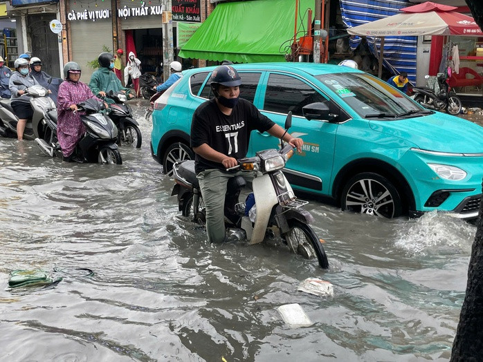 Người dân vất vả lưu thông qua tuyến đường ngập.