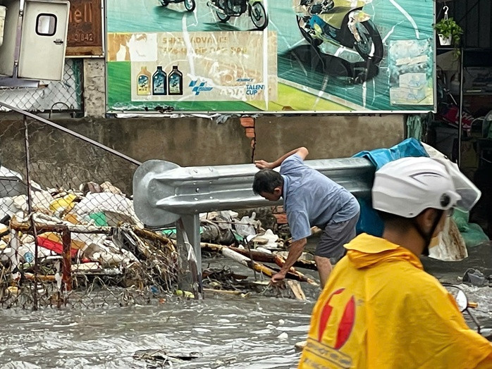Người dân vớt rác khỏi miệng cống thoát nước.