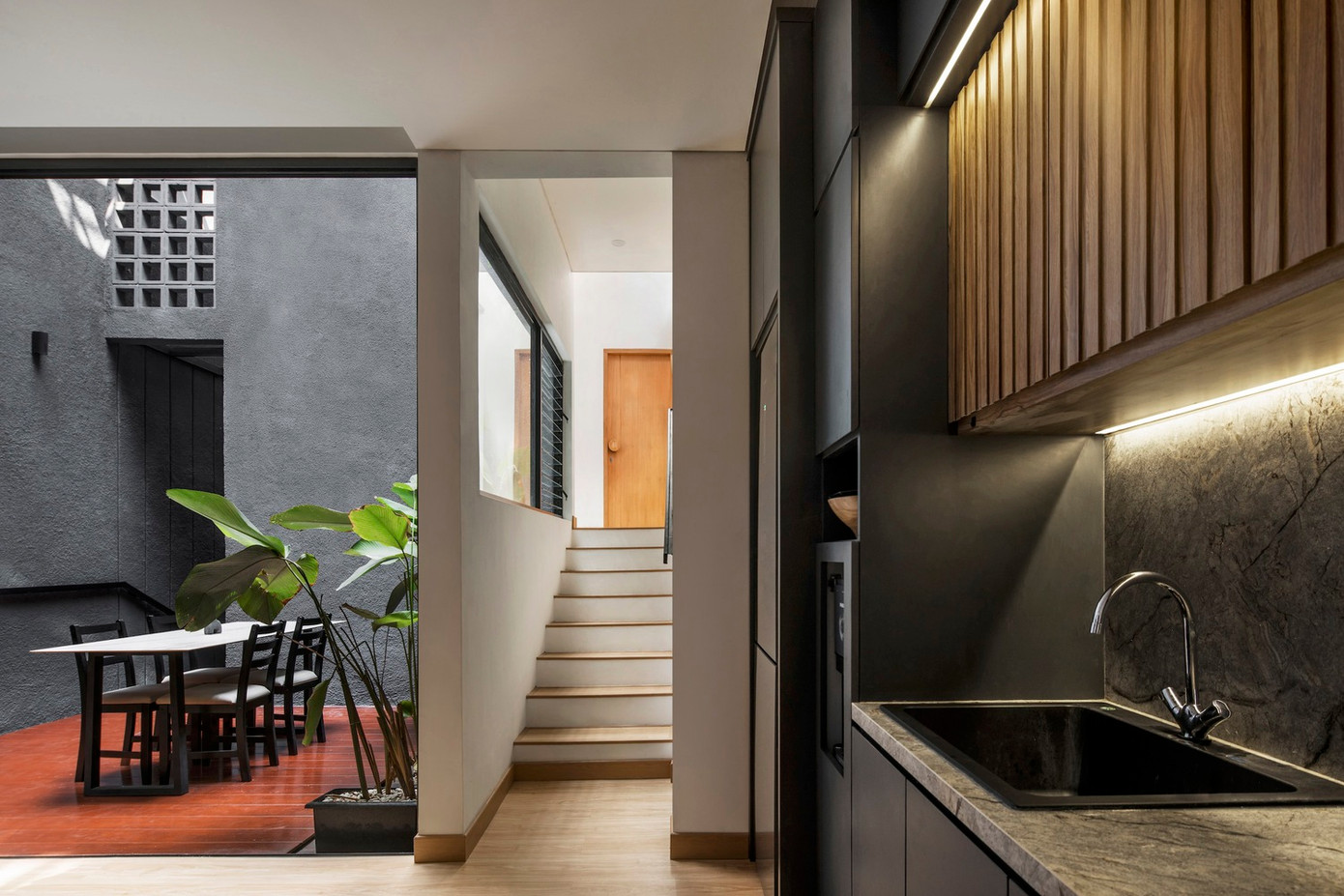 Khối phía sau trên tầng 1 có chức năng như một khu vực 3 trong 1 gồm phòng gia đình, nhà bếp và phòng ăn. Điểm độc đáo là phòng ăn không nằm sát khu bếp sạch sẽ như cách bố trí thông thường mà được đặt trong không gian mở và nối liền hai khối công trình.