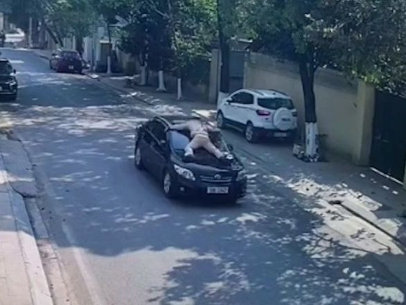 Hình ảnh CSGT bị hất lên nóc ca pô ô tô.