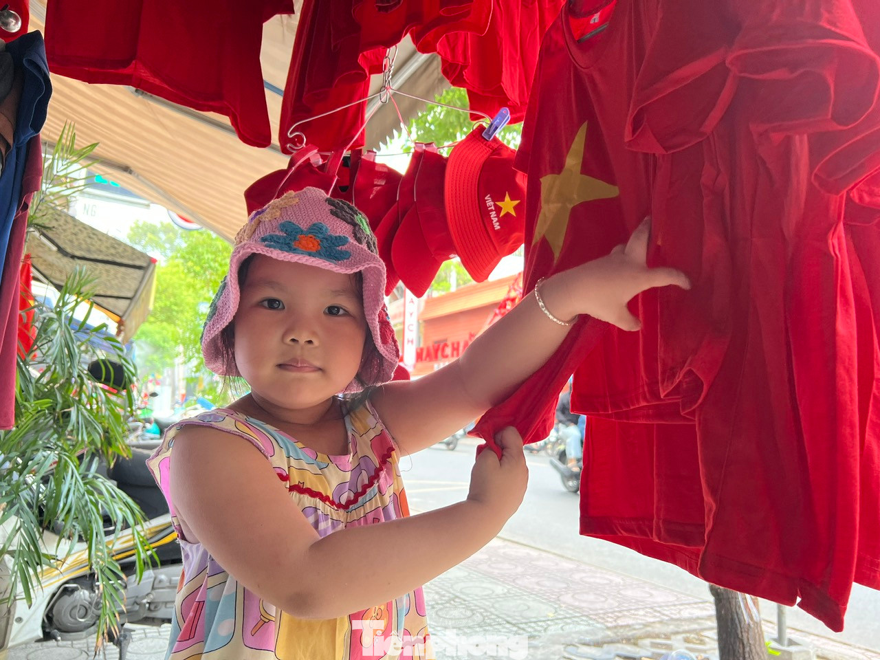 Một em bé vui thích được mẹ mua cho áo mới có hình sao vàng để mặc xem đại lễ