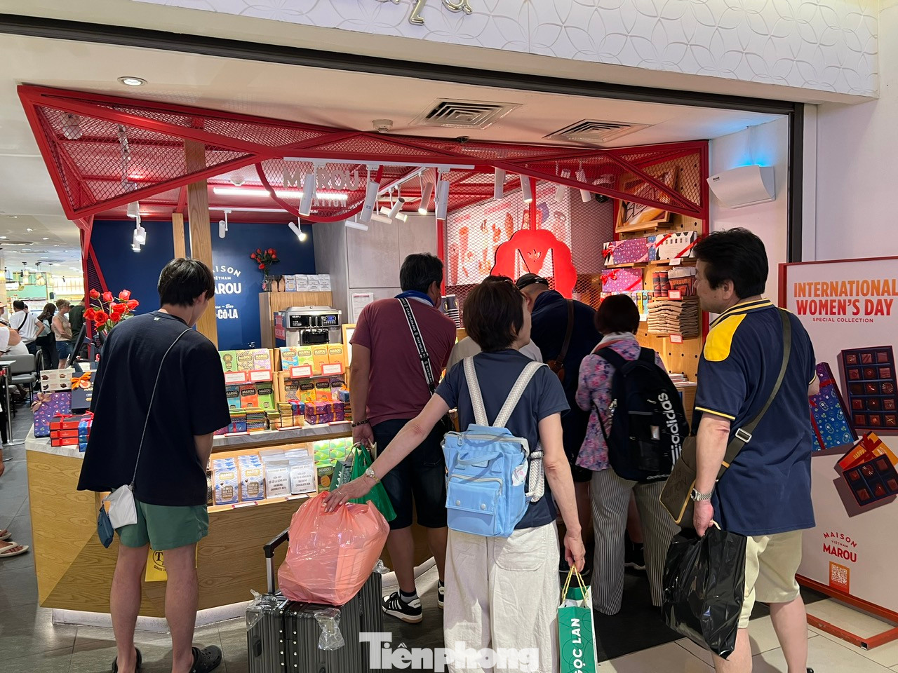 Nhiều du khách còn mang cả hành lý theo, trật tự xếp hàng chờ được phục vụ.