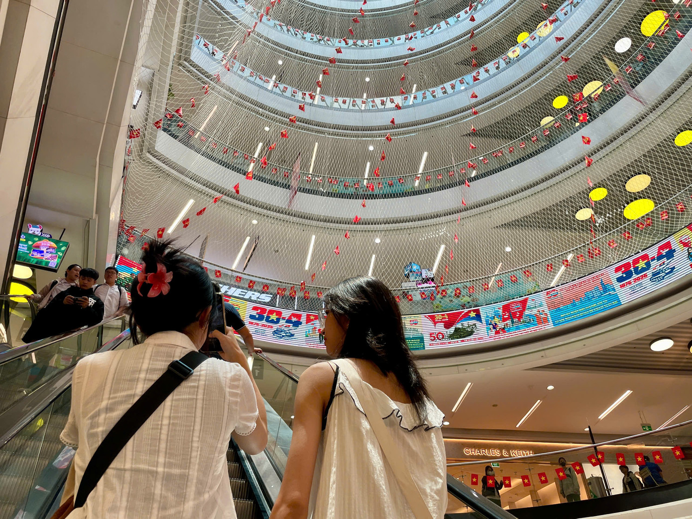 Trung tâm thương mại Vạn Hạnh Mall cũng tấp nập khách đến vui chơi. Nhiều khách hàng thích thú "check-in" với tấm lưới thông tầng được trang trí bằng cả trăm lá cờ tổ quốc rực rỡ.
