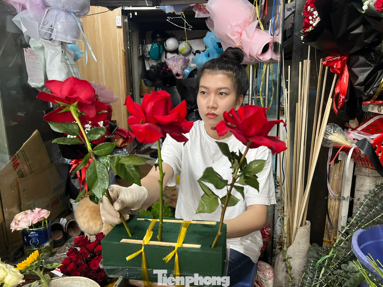 Nhân viên tiệm hoa cắm hoa theo yêu cầu của khách.