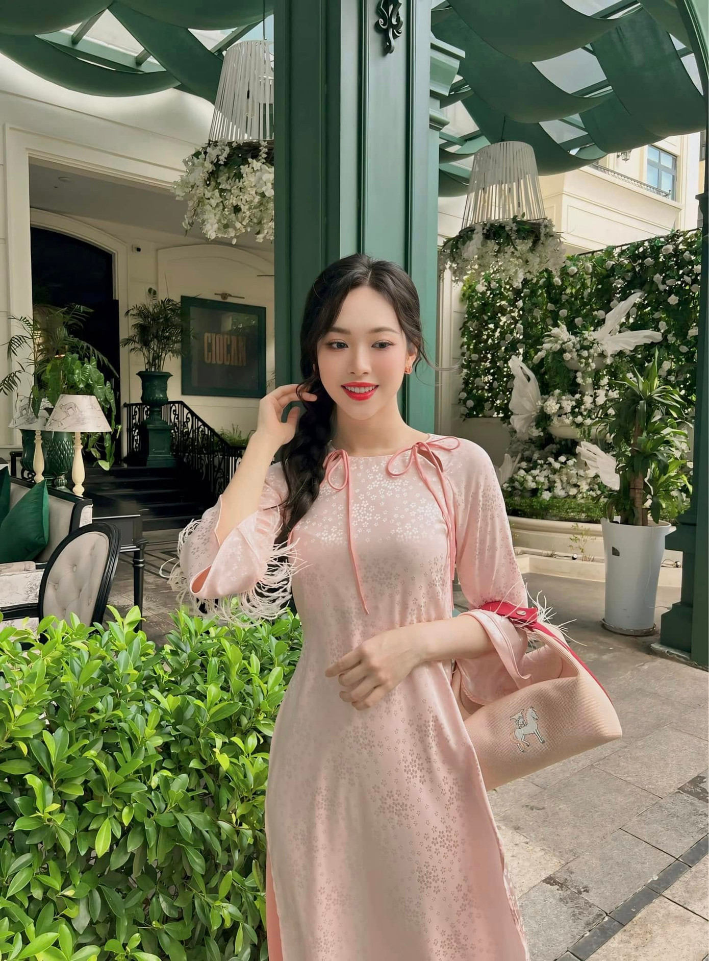 Á hậu Trịnh Thùy Linh chọn áo dài tông màu hồng pastel dịu dàng. Cô khéo léo phối cùng túi xách, dép bệt cùng tông màu. Người đẹp Thanh Hóa được khen khéo léo chọn áo dài tôn số đo ba vòng chuẩn.