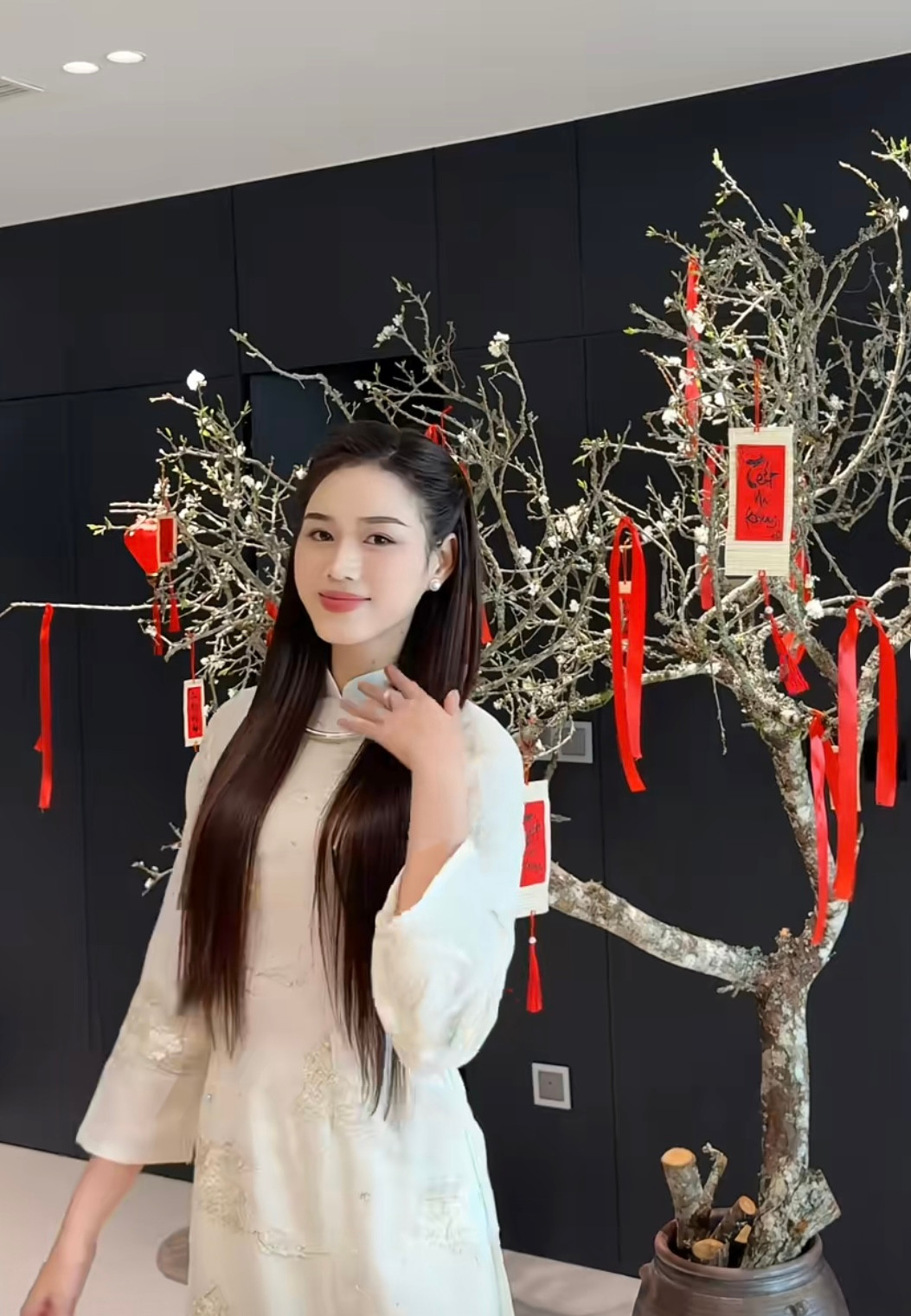Hoa hậu Đỗ Thị Hà cắm một cành đào cỡ lớn trong không gian phòng khách để chuẩn bị đón Tết. Người đẹp trang trí cho cành đào bằng những đồ decor tông màu đỏ cầu kỳ, nổi bật. Hoa hậu Việt Nam 2020 diện áo dài, hào hứng chụp ảnh bên cành đào sau khi được trang trí lộng lẫy.