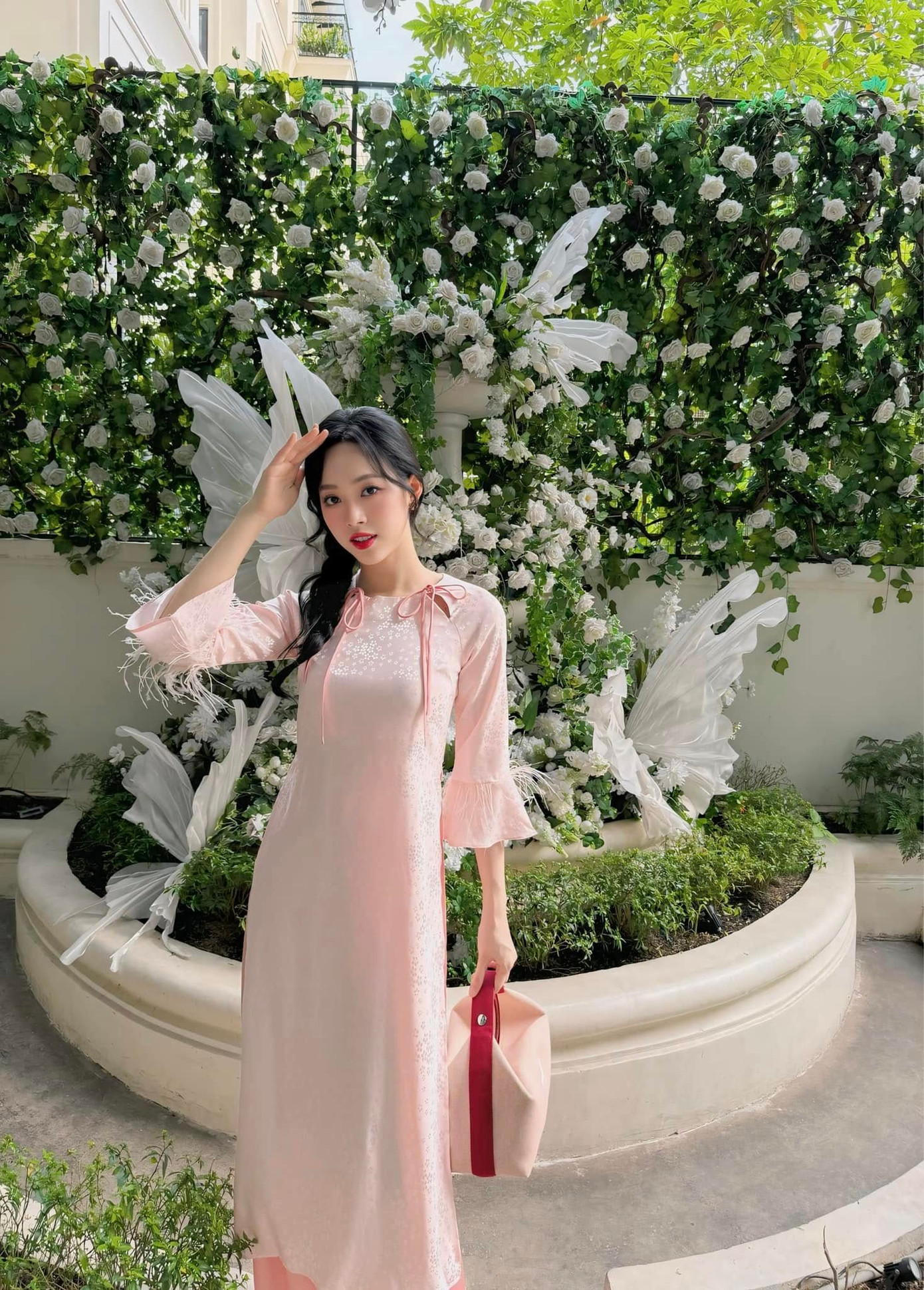 Á hậu Trịnh Thùy Linh chọn áo dài tông màu hồng pastel dịu dàng. Cô khéo léo phối cùng túi xách, dép bệt cùng tông màu. Người đẹp Thanh Hóa được khen khéo léo chọn áo dài tôn số đo ba vòng chuẩn.