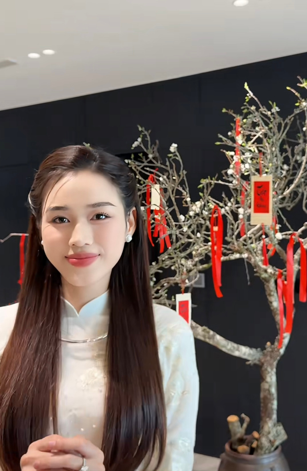 Hoa hậu Đỗ Thị Hà cắm một cành đào cỡ lớn trong không gian phòng khách để chuẩn bị đón Tết. Người đẹp trang trí cho cành đào bằng những đồ decor tông màu đỏ cầu kỳ, nổi bật. Hoa hậu Việt Nam 2020 diện áo dài, hào hứng chụp ảnh bên cành đào sau khi được trang trí lộng lẫy.