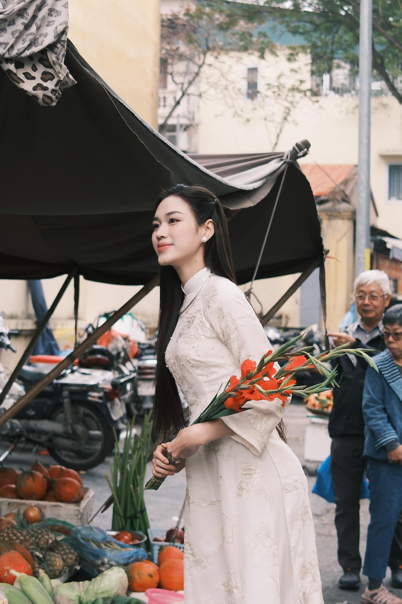 Hoa hậu Đỗ Thị Hà diện áo dài trắng họa tiết đi chợ Xuân những ngày cận Tết. Cô mặc áo dài lụa, kiểu dáng suông, tông màu nền nã.