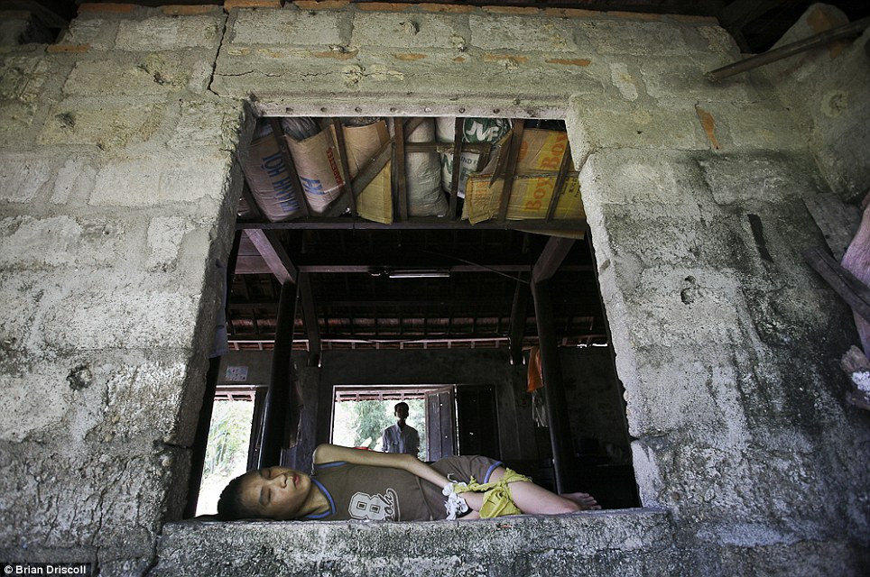 Một người lính Việt Nam đứng đằng sau con trai của ông Nguyễn Văn Dũng, 12 tuổi, tại nhà ở huyện Kim Động, Hải Phòng, Việt Nam