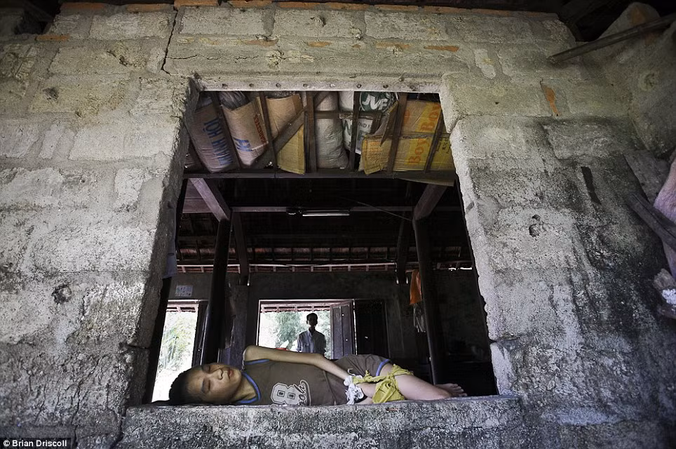 Một người lính Việt Nam đứng đằng sau con trai của ông Nguyễn Văn Dũng, 12 tuổi, tại nhà ở huyện Kim Động, Hải Phòng, Việt Nam